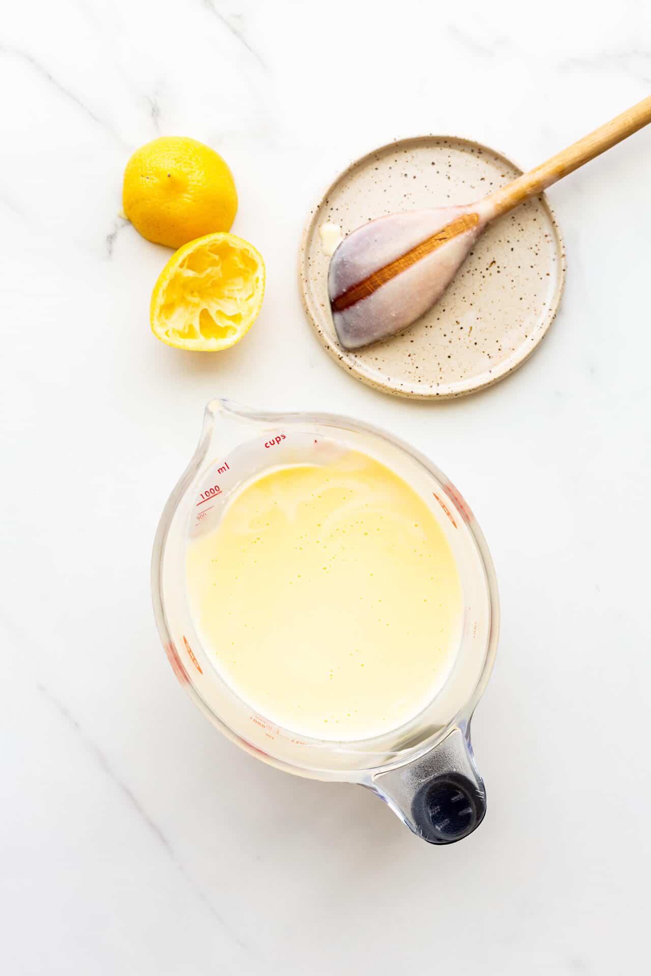 Custard base for lemon ice cream with spoon on plate to show the custard coats the back of the spoon