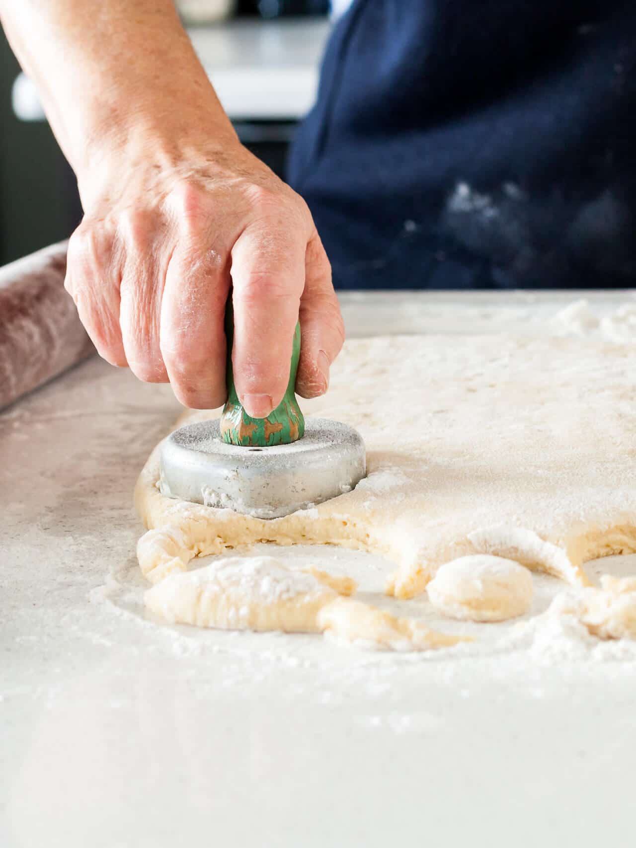 Cutting out donuts with an old-fashioned donut cutter with a wooden handle