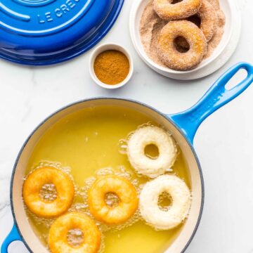 Frying donuts in a Le Creuset blue enamelware sauté pan then coating donuts in granulated sugar