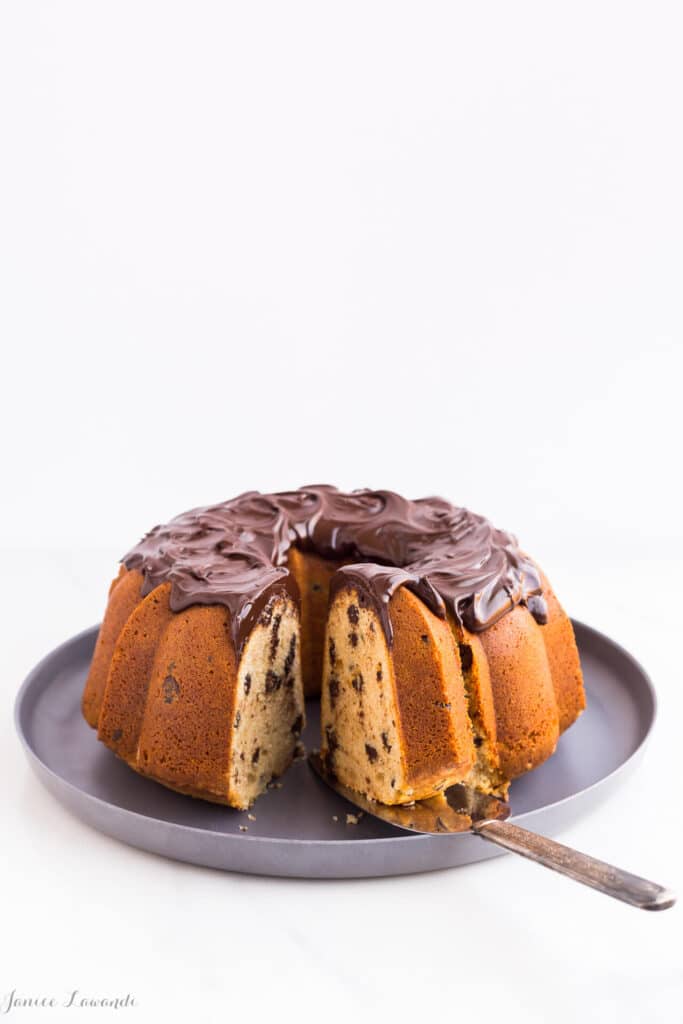 A slice of easy chocolate chocolate chip bundt cake made with sour cream and topped with a layer of chocolate ganache