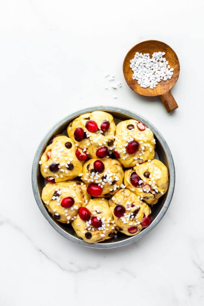 Chocolate cranberry brioche buns proofed, brushed with egg and sprinkled with coarse sugar, and ready to be baked.