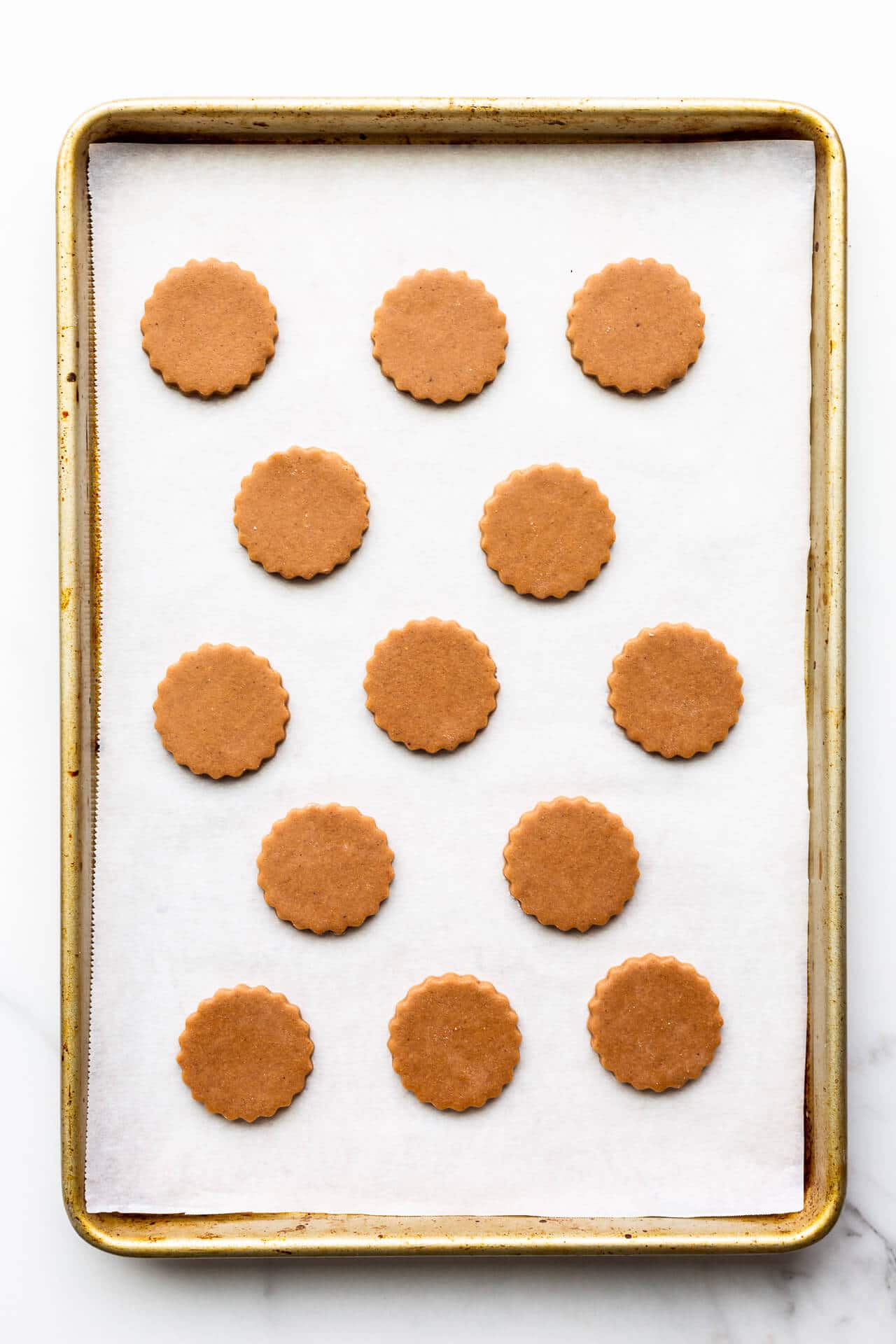 German gingerbread cookie cutouts on a parchment-lined sheet pan ready for the oven.