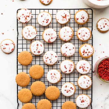 Gingerbread cookies being glazed on a black cooling rack.