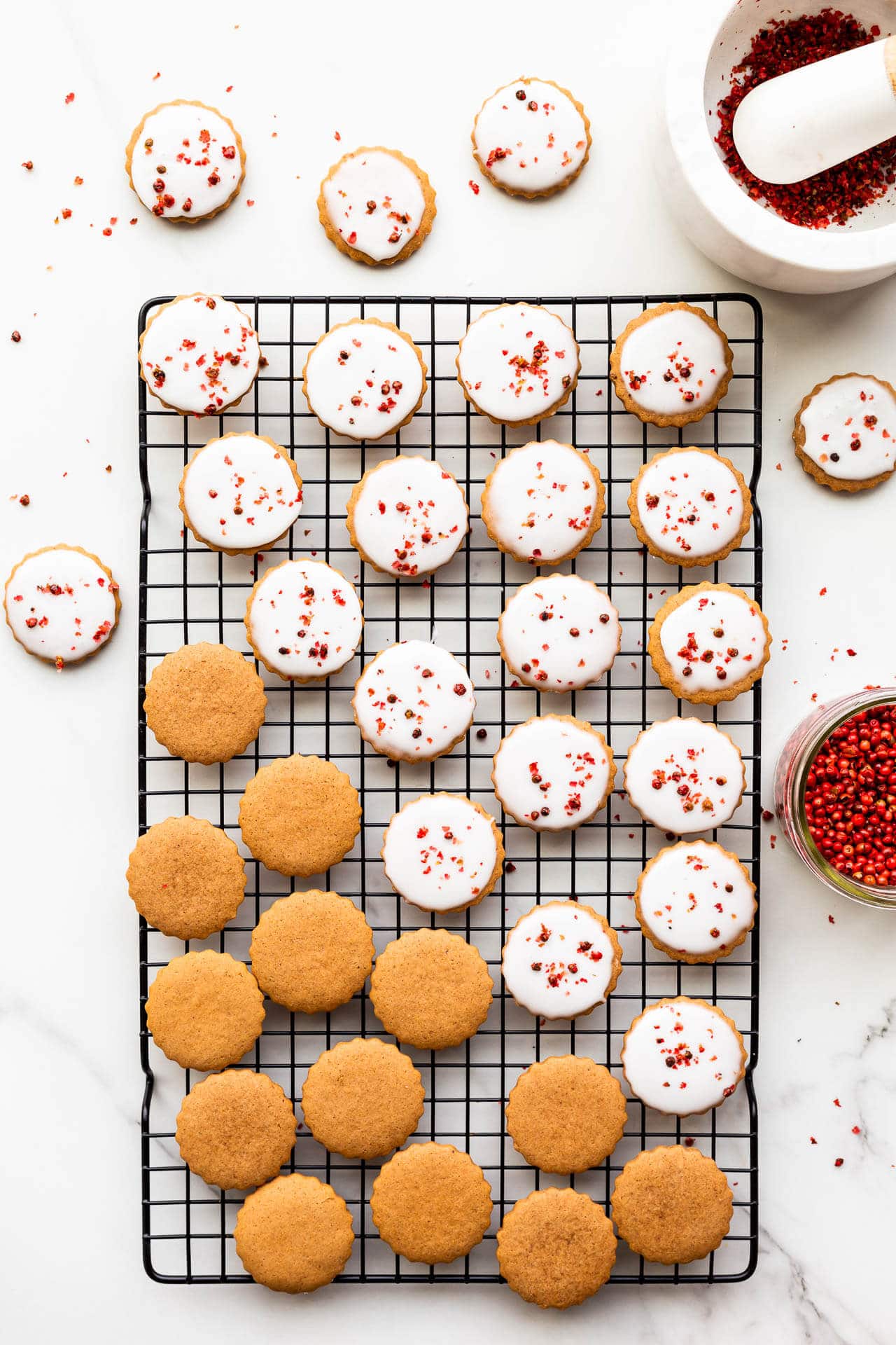 Gingerbread cookies being glazed on a black cooling rack.