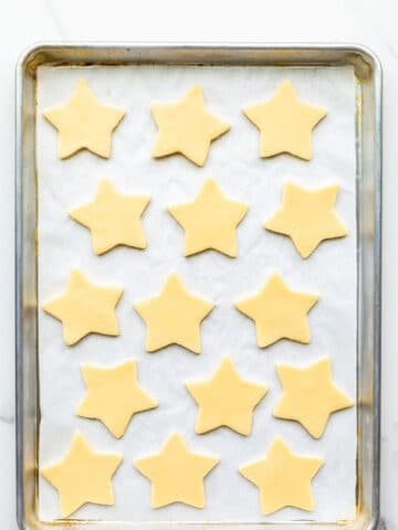 A sheet pan of cut out shortbread cookie stars ready to be baked.