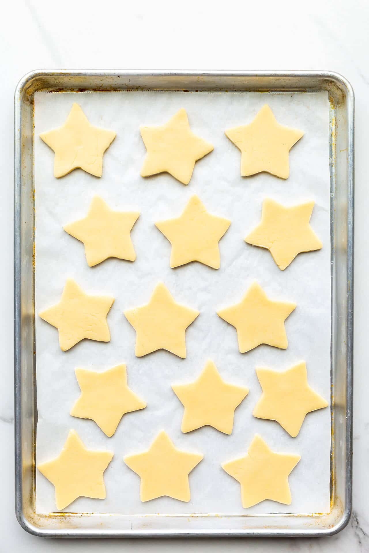 A sheet pan of cut out shortbread cookie stars ready to be baked.