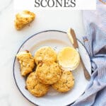 Baked lavender white chocolate scones on a blue-rimmed white enamelware plate with butter and a butter knife, blue and white striped napkin