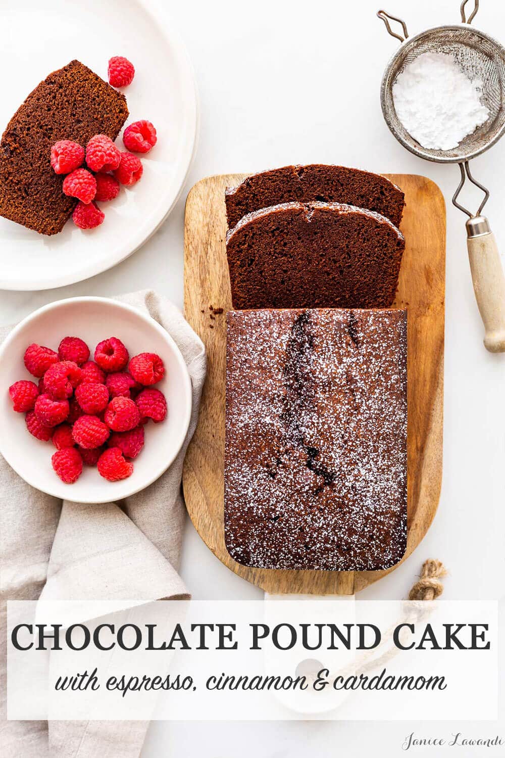 Chocolate pound cake sliced on a wood cutting board and served with a dusting of powdered sugar and fresh raspberries