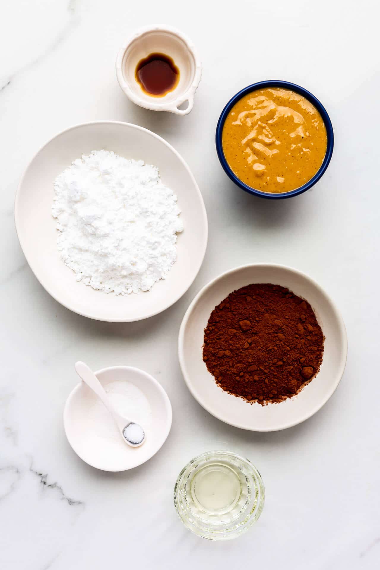 ingredienser til fremstilling af hjemmelavet chokolade jordnøddesmør spredning inkluderer vaniljeekstrakt, jordnøddesmør, pulveriseret sukker, kakaopulver, salt og lidt rapsolie.