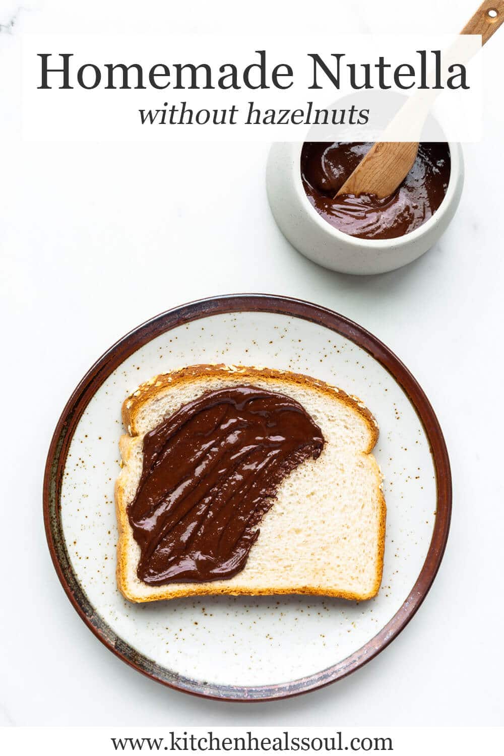 Homemade chocolate peanut butter spread on white bread on ceramic speckled plate with brown rim, with bowl of spread and wood knife nearby.