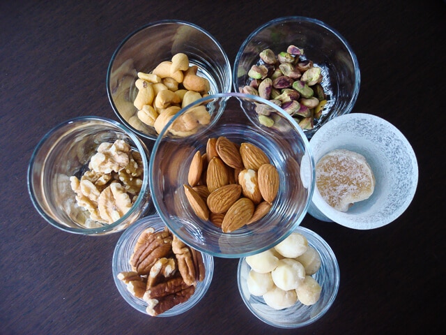 A variety of raw nuts in small glasses, almonds, walnuts, cashews, pistachios, macadamia nuts, pecans