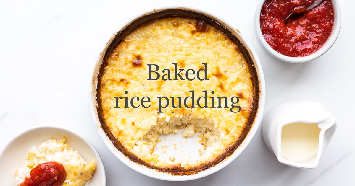 Baked rice pudding in a baking dish with dark golden brown edges with rhubarb compote and cream on the side