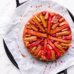 Raspberry rhubarb upside down cake on a parchment lined black round tray