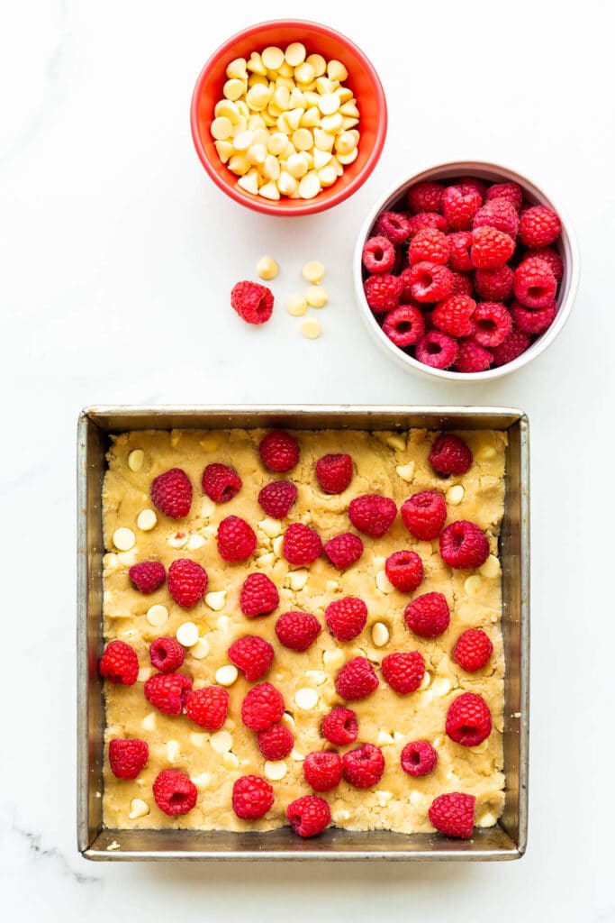 White chocolate chip blondie bars topped with fresh raspberries before baking