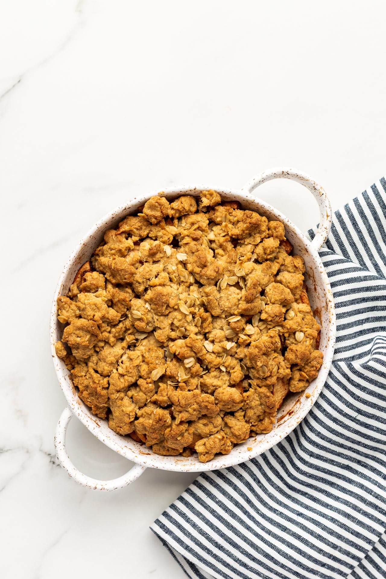 Freshly baked apple crisp with oat crumble and blue and white linen