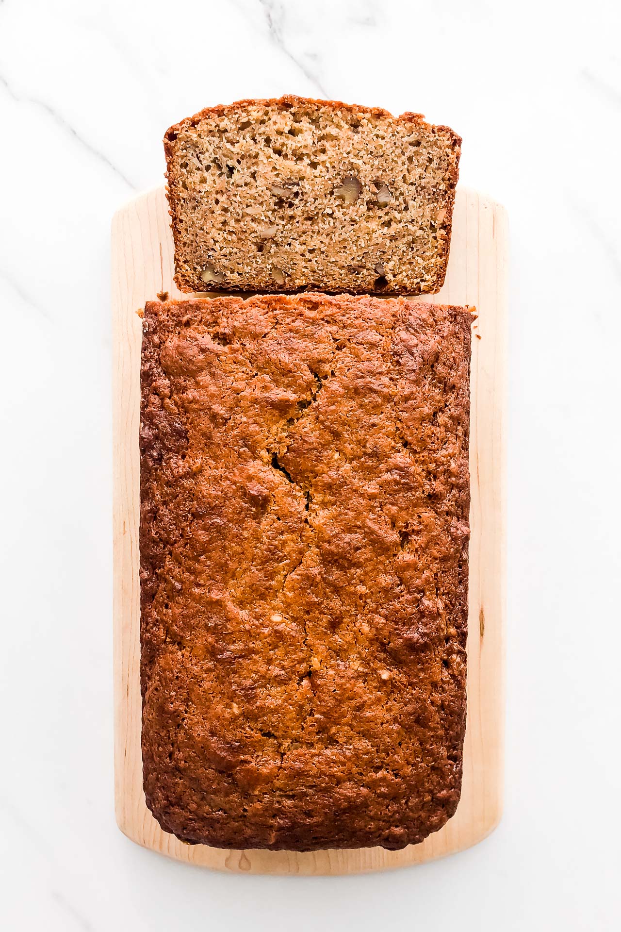 Cardamom banana bread made with sour cream and walnuts, sliced on a wood cutting board