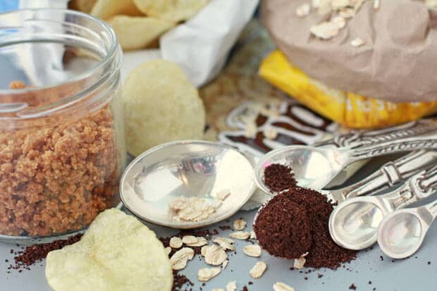 Ingredients for everything cookies or compost cookies include a jar of graham cracker crust, potato chips, oats, chocolate chips, and coffee grinds