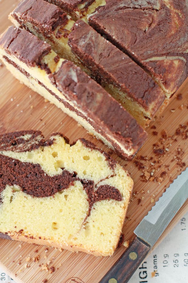 A loaf of chocolate marble cake sliced with a serrated knife