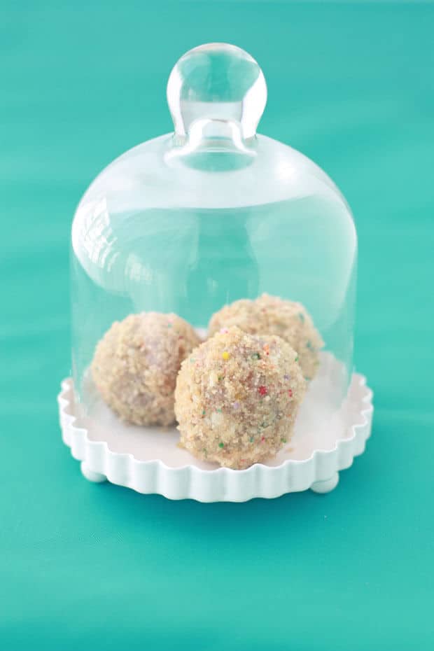 Three sprinkle cake truffles under a mini cake cloche