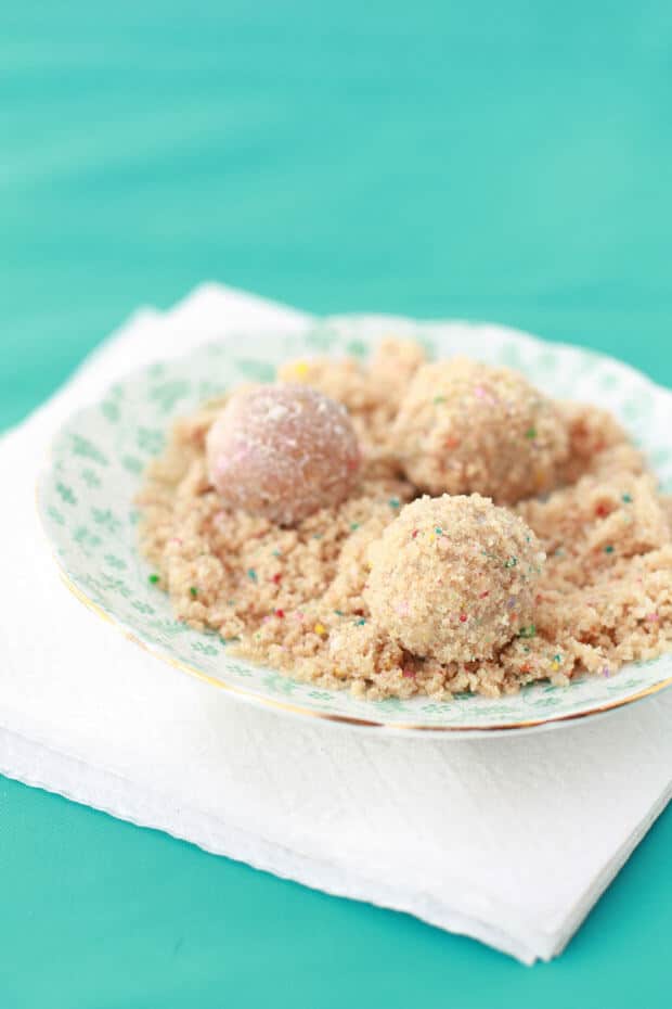 Coating birthday cake truffles in birthday cake crumbs in a little floral saucer 