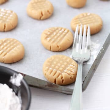 pressing peanut butter cookie dough with a fork for the criss cross pattern