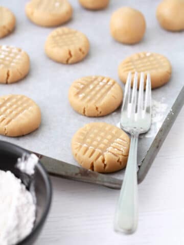 pressing peanut butter cookie dough with a fork for the criss cross pattern
