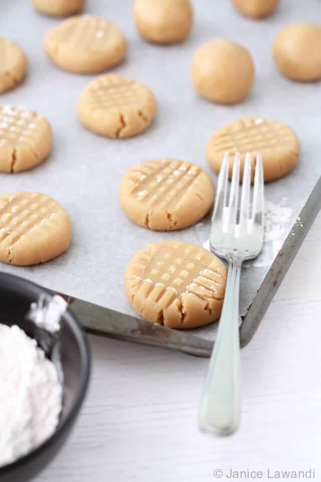 Pressing peanut butter cookie dough with a fork for the criss cross pattern.