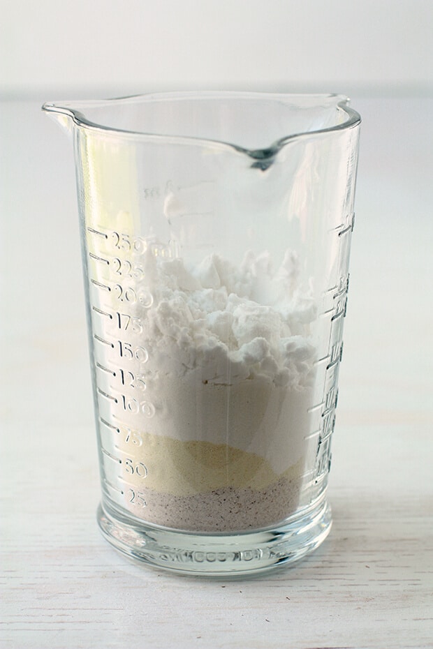 Homemade gluten free flour mix in a measuring cup to show the layers of different flours and starches used to make the mix