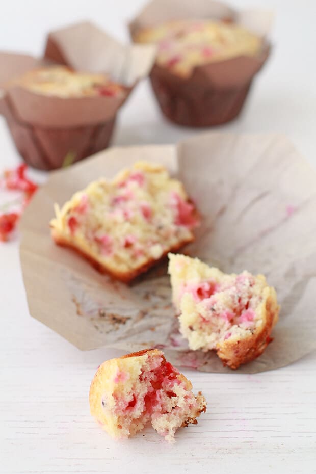 Homemade red currant muffins baked in brown parchment liners and broken open to show the inside