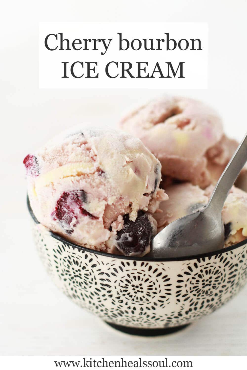 Cherry bourbon ice cream scooped in a black and white bowl and served with a spoon