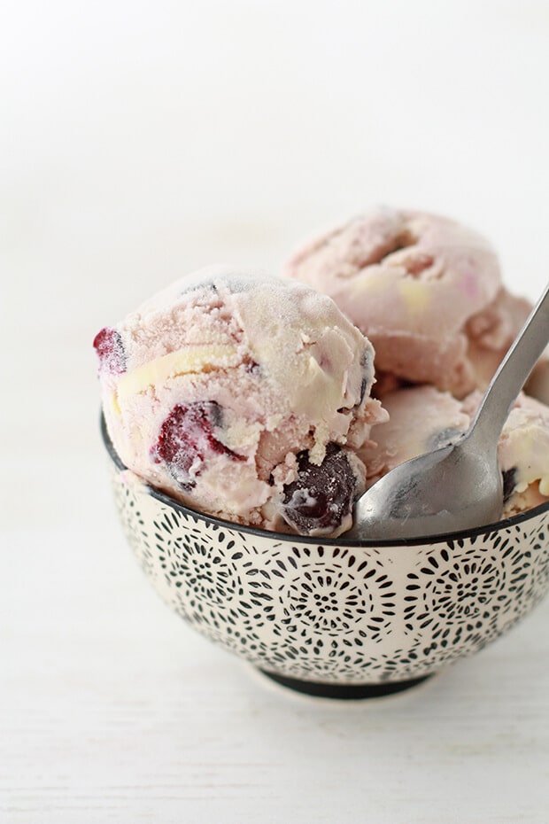 Scooped homemade cherry bourbon ice cream in a black and white bowl