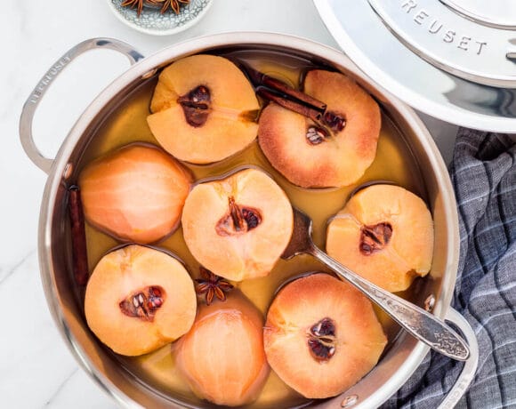 Poached quince cut in half in a sauté pan with simple syrup.