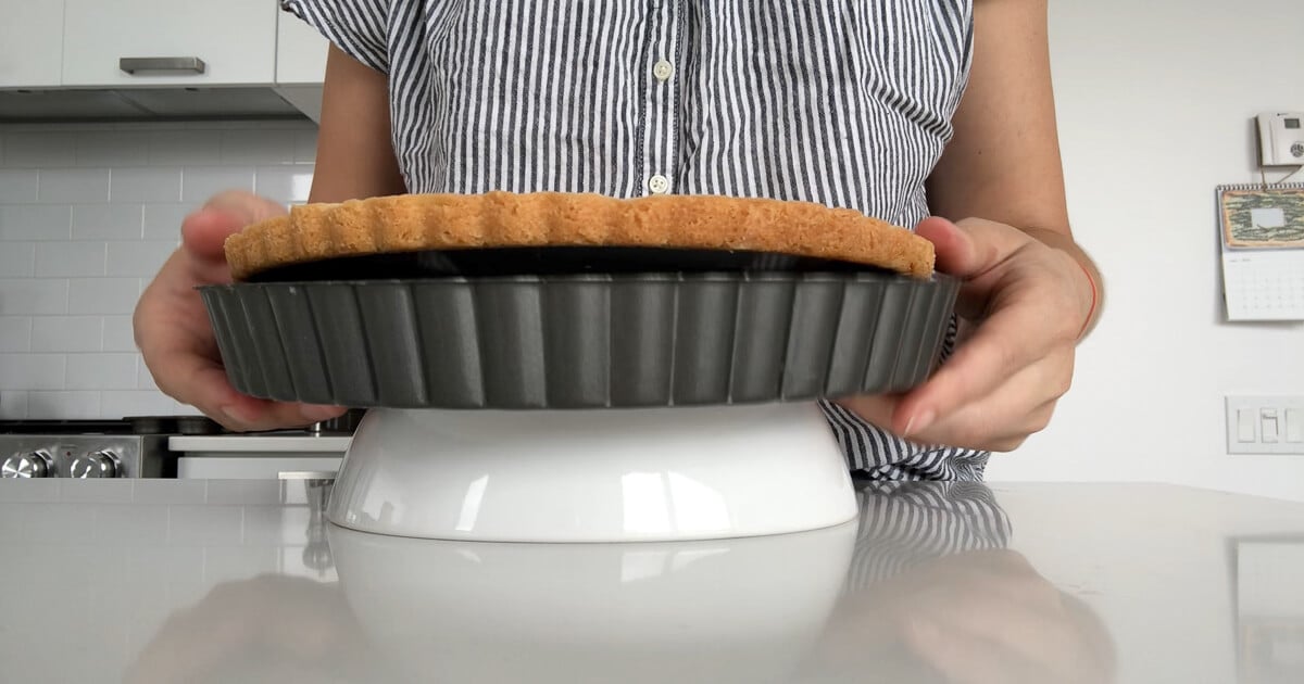 Removing a tart crust from a tart pan using an inverted bowl to separate the ring from the base.