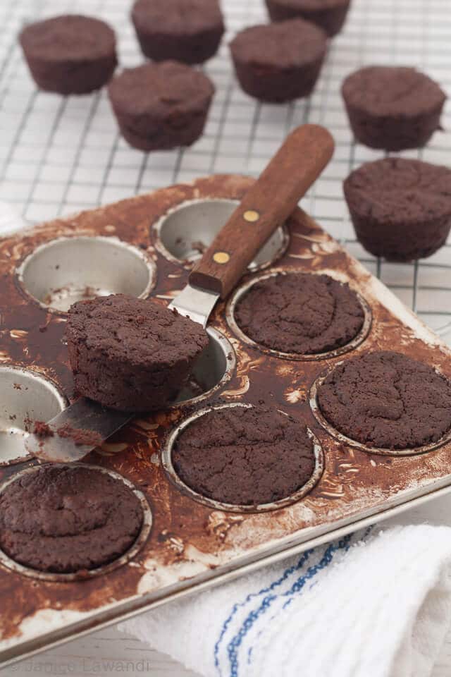 Unmoulding gluten-free brownies with peanut butter baked in a mini muffin pan that was greased and dusted with cocoa powder