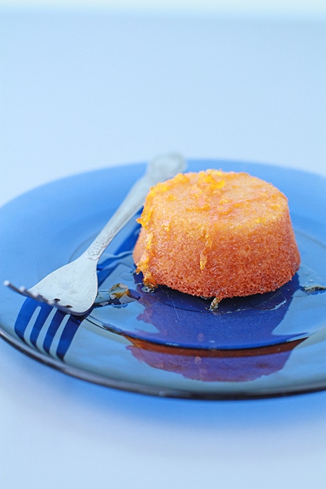 mini orange almond cake with orange syrup served on blue glass plate with fork