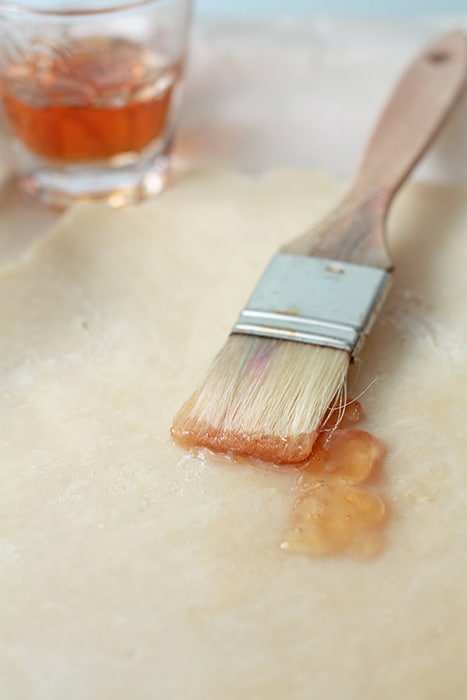 Brushing pie crust with apple jelly with a pastry brush