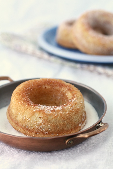 baked donut in a dish to coat them in sugar