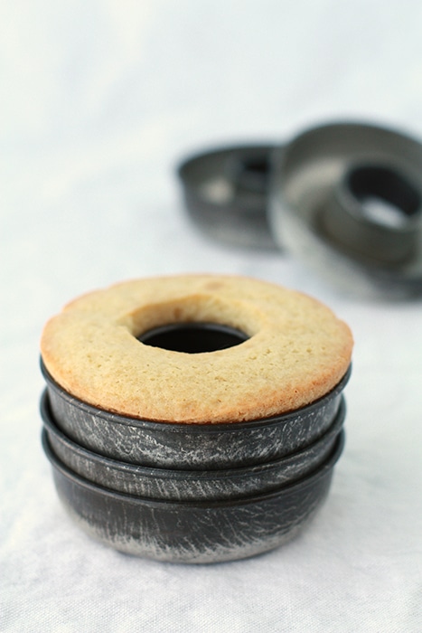 baked doughnuts in vintage donut pans stacked on white tablecloth