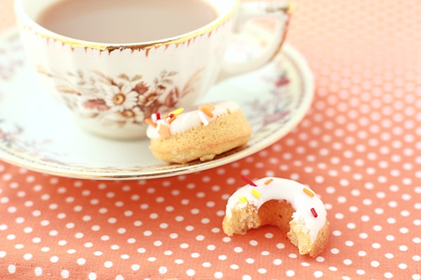 Baked pumpkin donuts and a cup of tea on an orange and white polka dot tablecloth