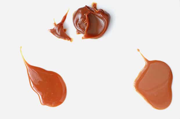 Comparison of three dollops of dulce de leche to show that the top one is much thicker than the two on the bottom.