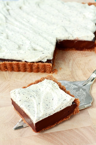 a square of chocolate tart with Earl Grey tea flecked whipped cream and a graham cracker crust placed on a silver server