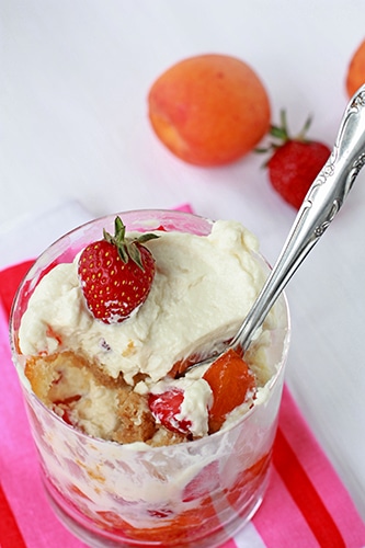 Portion of trifle in a glass with layers of berries, cake, and cream.