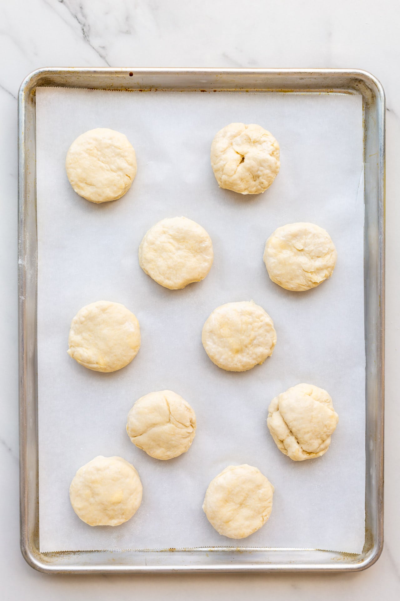 Homemade biscuits on a parchment-lined baking sheet ready to be baked