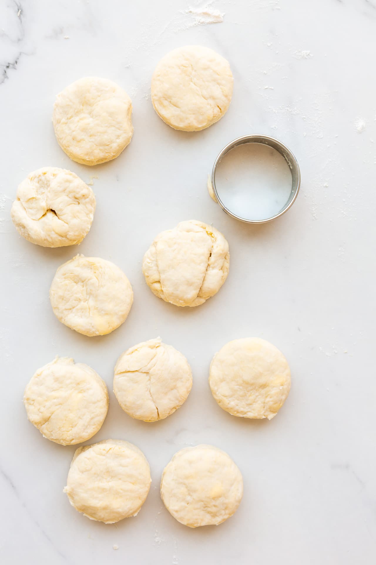 A round cookie cutter next to freshly cut homemade biscuits, ready to be baked