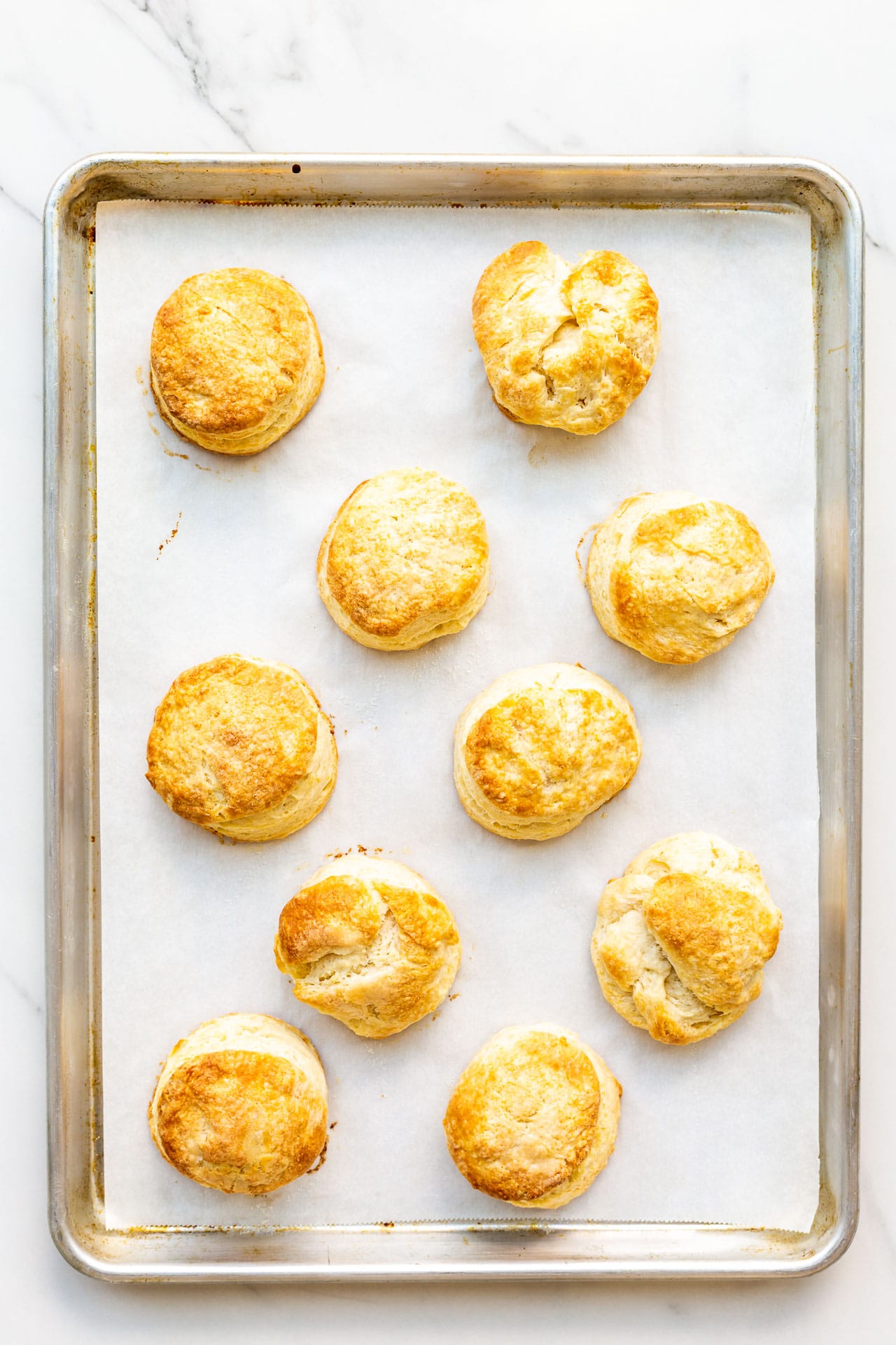 A parchment-lined sheet pan with golden brown homemade biscuits