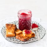 A jar of plum jam served with toast.