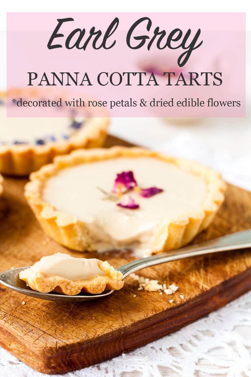 Earl Grey panna cotta tart topped with dried rose petals and cut into with a fork, served on a wooden cutting board placed on a white lace doily
