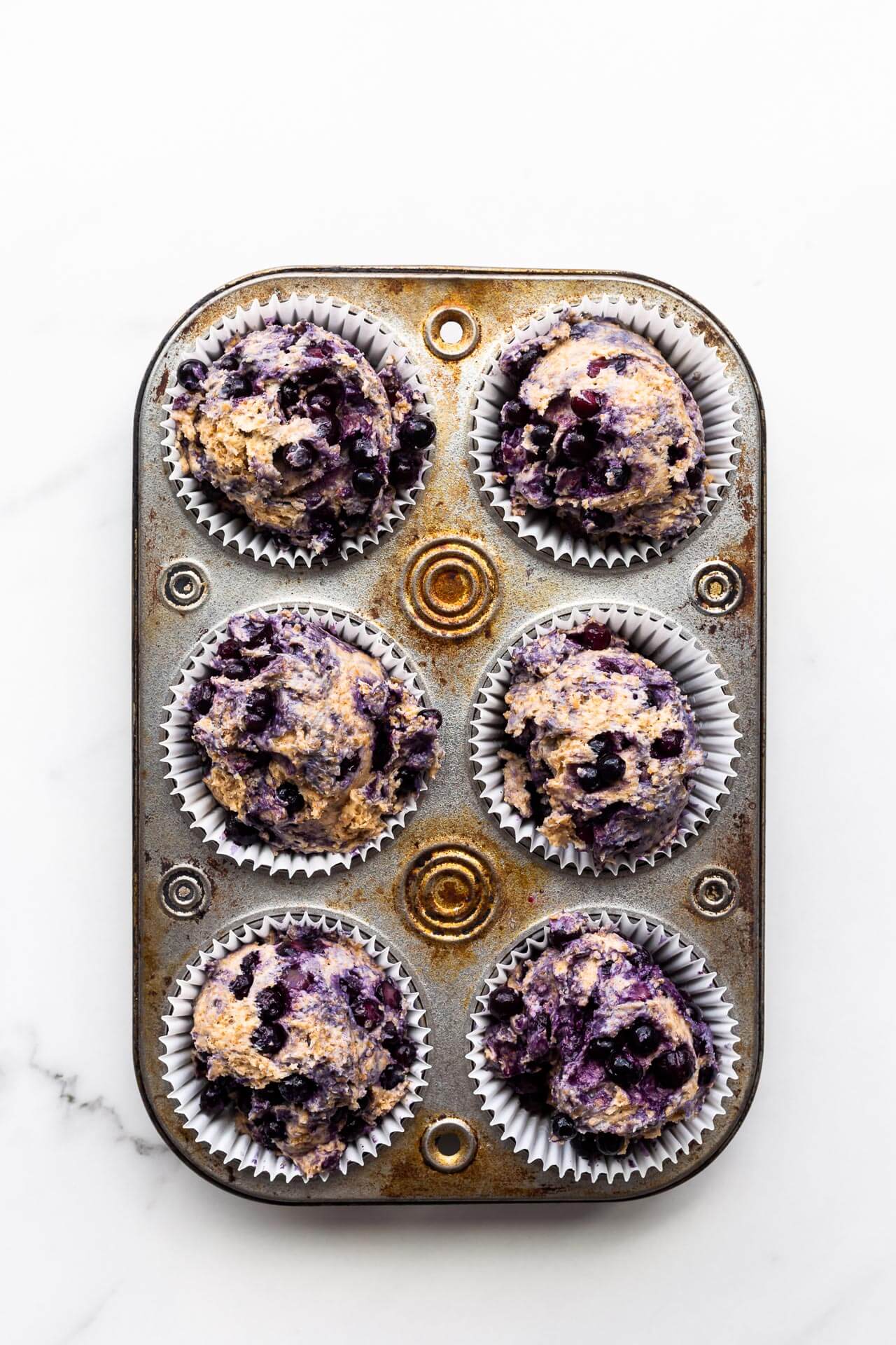 Blueberry bran muffins divided between paper liners in a vintage muffin pan