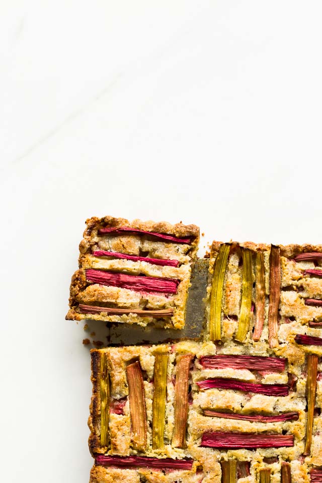 Rhubarb pumpkin seed cake sliced into squares with woven rhubarb pattern