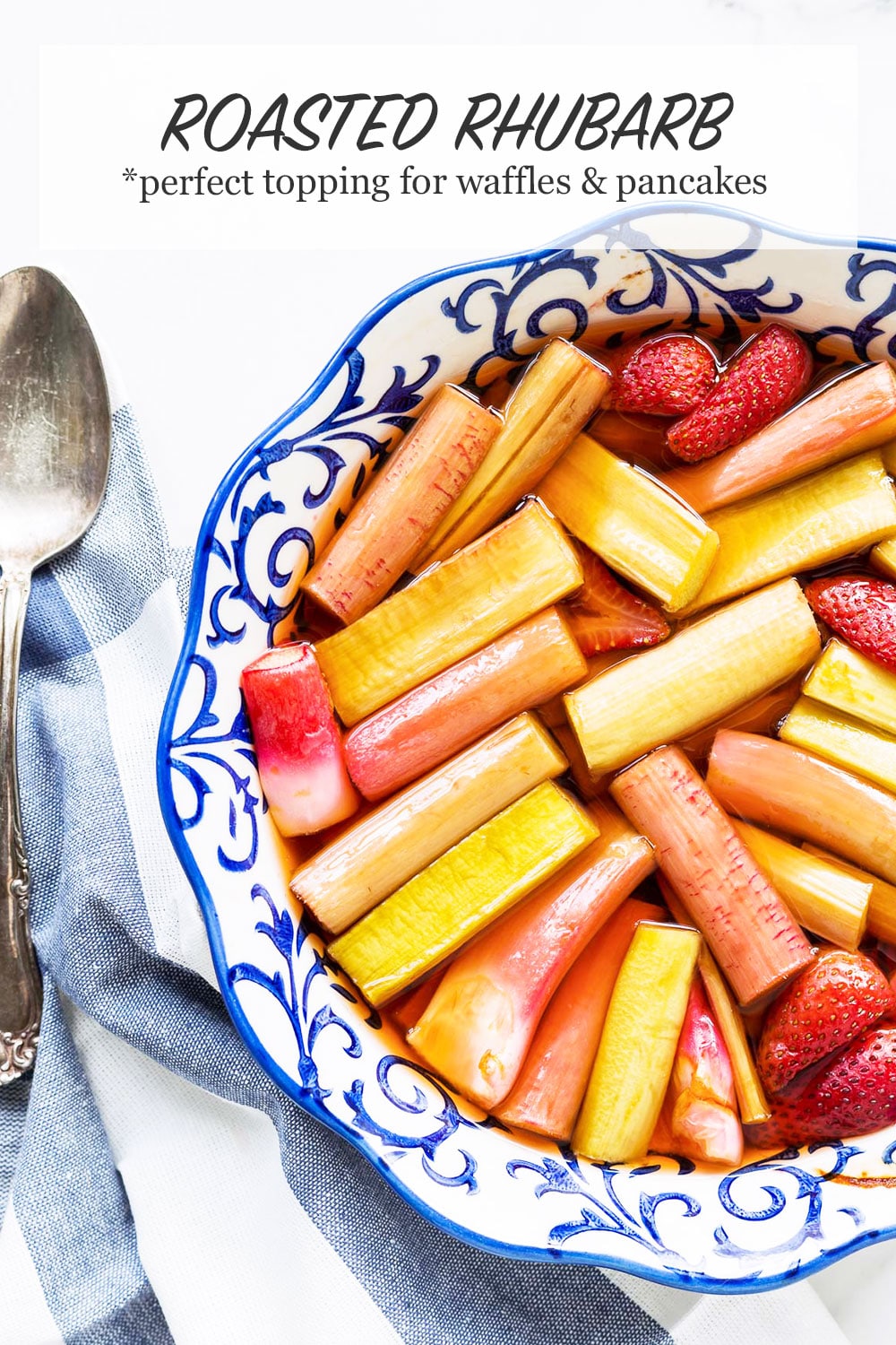 A blue and white round ceramic baking dish with roasted pink rhubarb and a few strawberries in pink syrup with blue and white striped linen and big vintage serving spoon